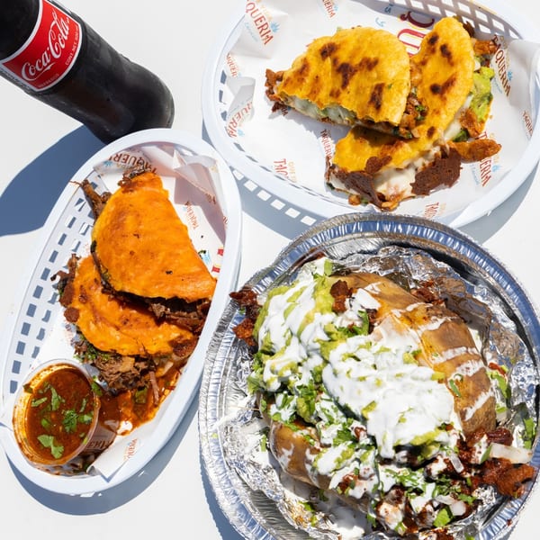 Que Vida Taqueria's birria tacos, quesabirria, and a loaded baked potato with a Coca-Cola.