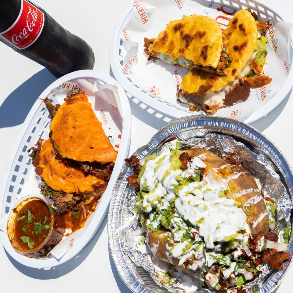 Que Vida Taqueria's birria tacos, quesabirria, and a loaded baked potato with a Coca-Cola.