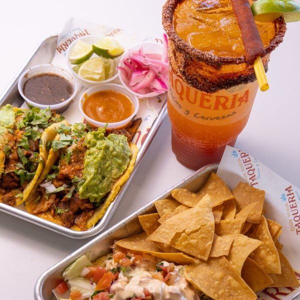 Que Vida Taqueria's tacos, chips and queso, and a large michelada drink with a chili straw.
